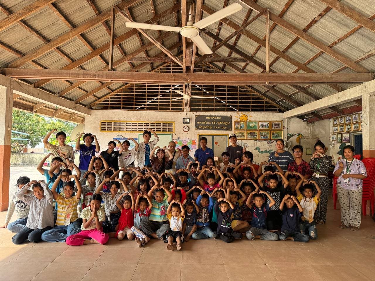 Children, staff and volunteers making heart shapes with their hands