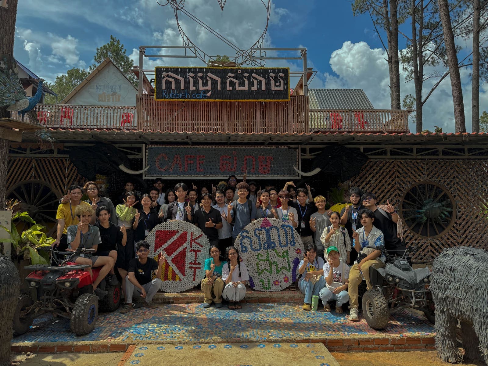 The volunteer group in front of Rubbish Cafe with a KIT logo made of bottle caps